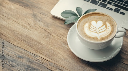 A cozy coffee scene featuring a latte art heart design beside a laptop on a wooden table, perfect for work or relaxation. photo