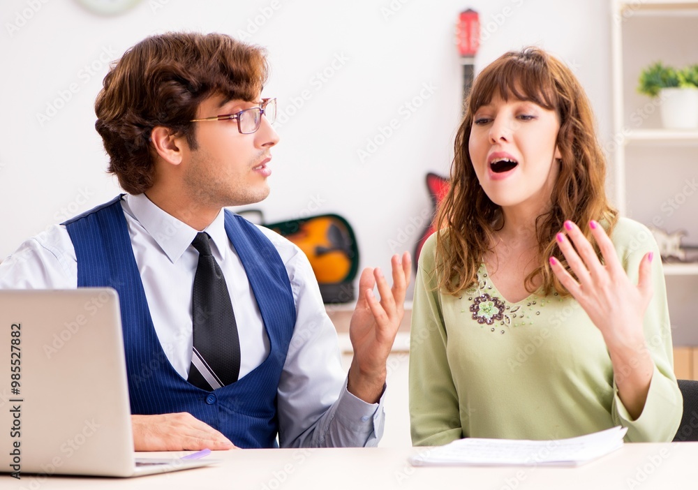 Young woman during music lesson with male teacher Young woman during music lesson with male teacher