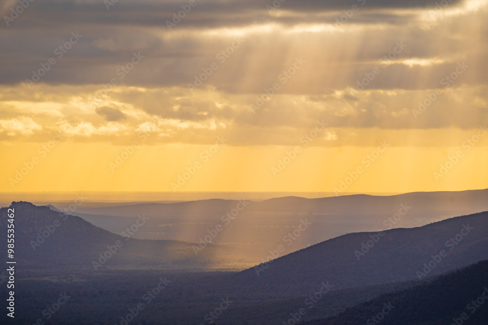 Distant view of golden rays of sunlight over a mountain range Distant view of golden rays of sunlight over a mountain range