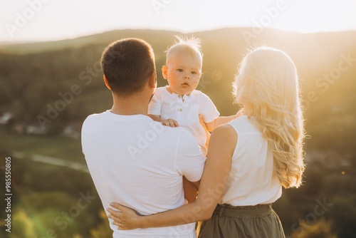 Tableau sur toile Happy Family Enjoying Sunset in Nature with Parents Holding Baby Outdoors