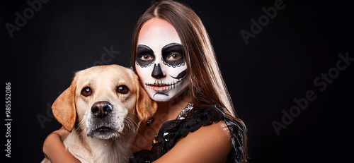 Donna con viso disegnato come un teschio mentre abbraccia un cane. sfondo nero