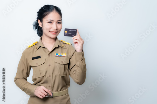 Beautiful Asian female teache pointing to empty copy space isolated on green background.