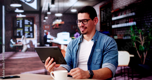 Hispanic Man Using Tablet In Coffee Shop