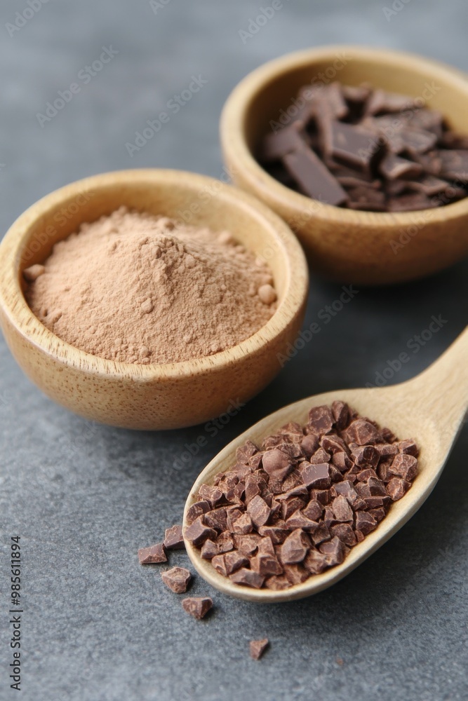 Cocoa powder and chocolate chunks in wooden bowls on gray stone surface Cocoa powder and chocolate chunks in wooden bowls on gray stone surface