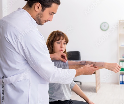 Young male doctor checking woman joint flexibility photo