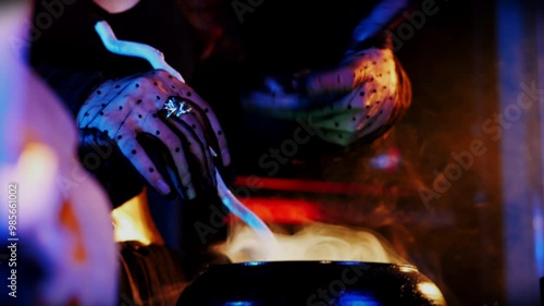 Close-up of a witch's hands over a pot of potion with white smoke coming out of it. The witch casts a spell. Mystical Halloween celebration concept. photo