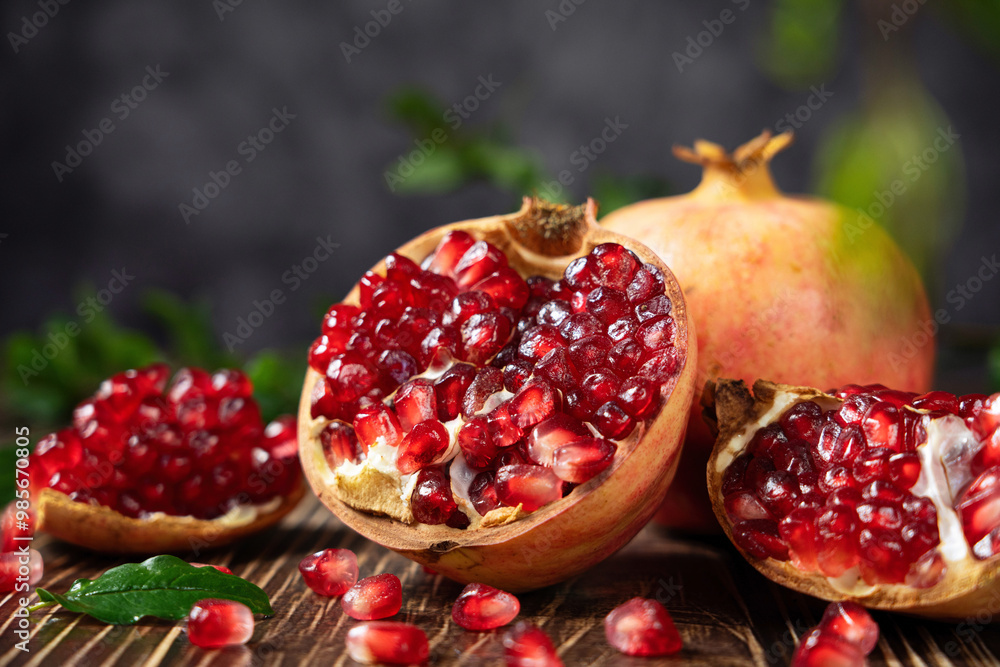 open pomegranates, and pomegranate seeds on wooden table. open pomegranates, and pomegranate seeds on wooden table.