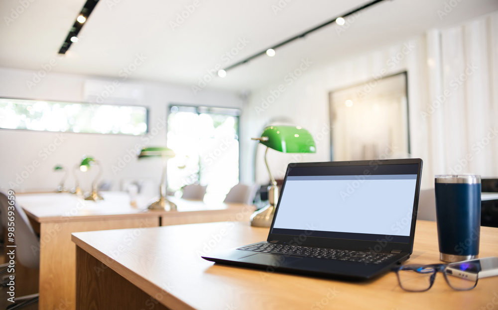 Comfortable workplace on wooden table in modern office with laptop, eyeglasses, mobile phone and coffee cup Comfortable workplace on wooden table in modern office with laptop, eyeglasses, mobile phone and coffee cup