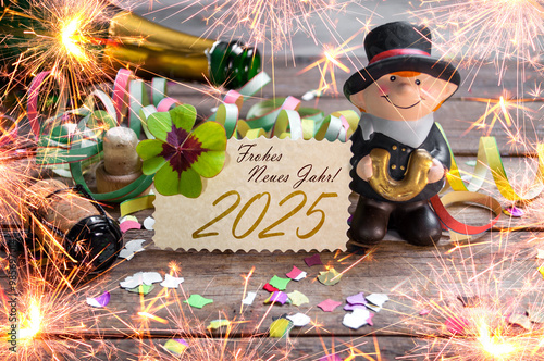 Wooden hang tag and slate with four leaf clover and sparklers with the german words for happy new year - frohes neues jahr 2025 on wooden weathered background	 photo