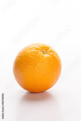 A single orange sits on a white background, showcasing its vibrant color and textured skin.