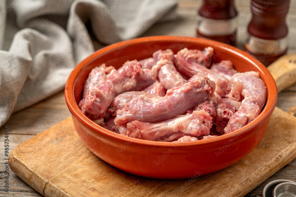 Raw chicken necks in a bowl close-up on a gray wooden culinary background
