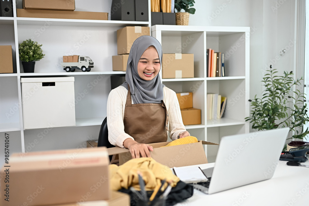Smiling muslim woman packing product for delivery to customers. Online selling and e-commerce concept Smiling muslim woman packing product for delivery to customers. Online selling and e-commerce concept