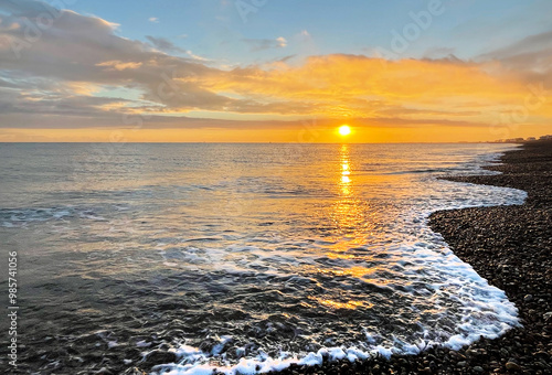 Sunset over a Kent beach with gentle waves lapping on the shore photo