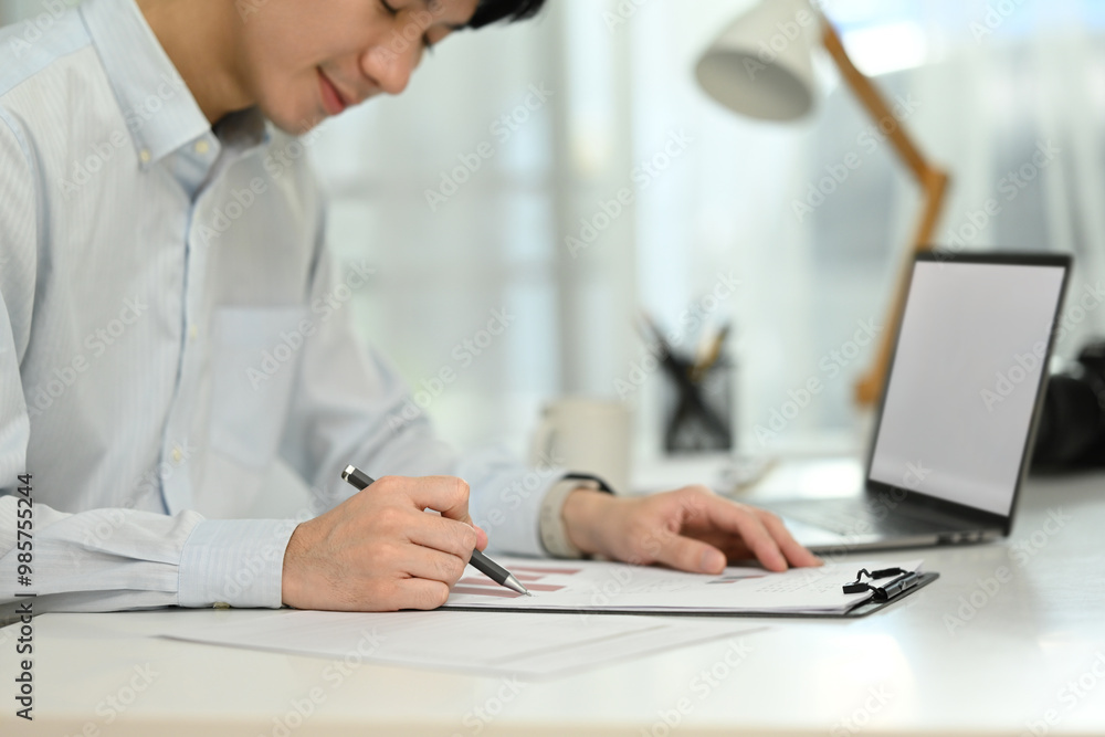 Fototapeta premium A man is writing on a piece of paper with a pen