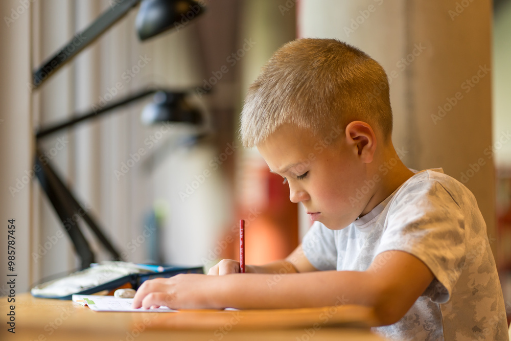 Schoolboy doing homework at a table in the city library Schoolboy doing homework at a table in the city library