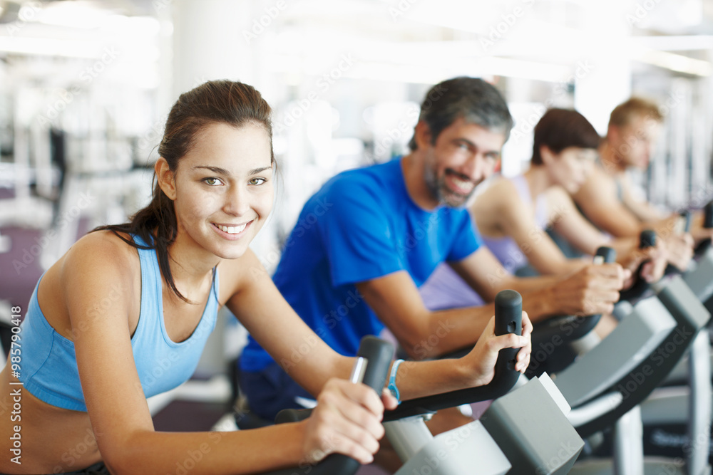 Group, spinning class or happy woman in training, bike and exercise for wellness, health and fitness. Smile, people or bicycle for cardio, strong legs or power for workout, body or sports for cycling Group, spinning class or happy woman in training, bike and exercise for wellness, health and fitness. Smile, people or bicycle for cardio, strong legs or power for workout, body or sports for cycling
