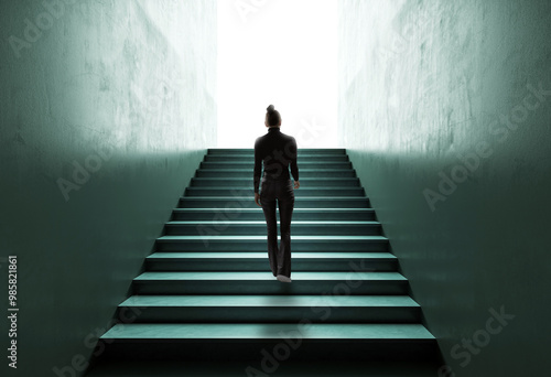 Photos Silhouette of a Woman Climbing Stairs Towards Light, Symbolizing Career Growth and Success