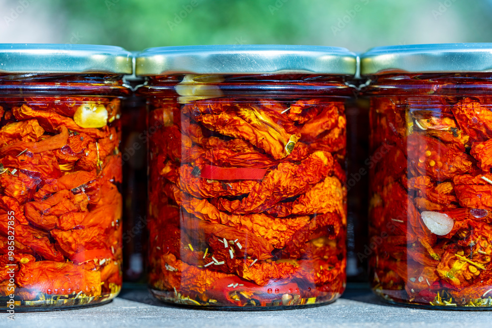 Sun-dried red tomato with garlic, rosemary, olive oil and spices in a glass jars on a wooden table. Rustic style, closeup Sun-dried red tomato with garlic, rosemary, olive oil and spices in a glass jars on a wooden table. Rustic style, closeup