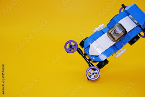 blue racing car assembled from plastic blocks. toy car isolated on yellow background photo