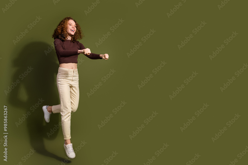 Full length photo of charming positive girl wear brown shirt rising kick bike empty space isolated green color background Full length photo of charming positive girl wear brown shirt rising kick bike empty space isolated green color background