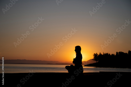 Cuadro en lienzo Young woman meditating by the sea at sunrise