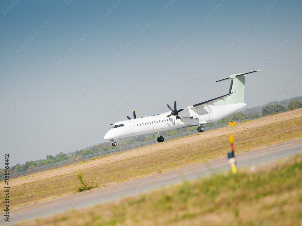Turboprop aircraft takes off on a runway on a sunny day. Two engine regional airliner leaves the ground and becomes airborne. Turboprop aircraft takes off on a runway on a sunny day. Two engine regional airliner leaves the ground and becomes airborne.
