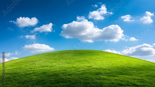 Green hill under a blue sky with clouds