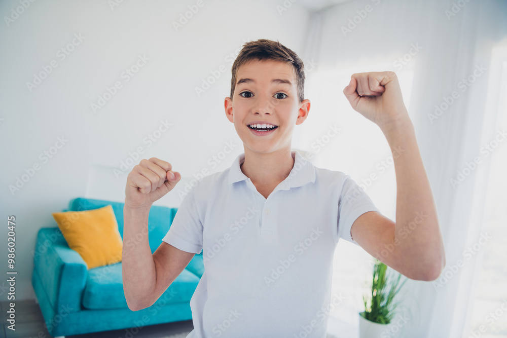 Portrait of charming little boy raise fists celebrate wear t-shirt modern interior flat indoors Portrait of charming little boy raise fists celebrate wear t-shirt modern interior flat indoors