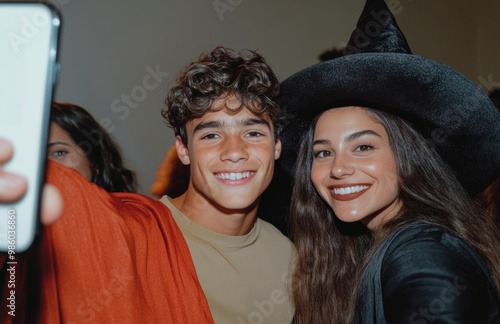 Three people are smiling for the camera, one of them wearing a red hat. Scene is happy and festive, as the people are posing for a photo during Halloween