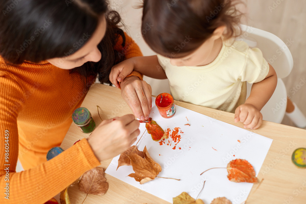 happy little child girl and her mother drawing for the autumn holiday. happy family painting autumn leaves happy little child girl and her mother drawing for the autumn holiday. happy family painting autumn leaves