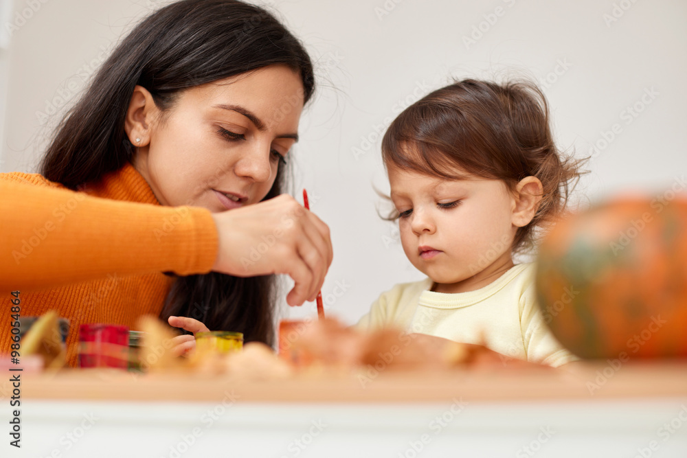happy little child girl and her mother drawing for the autumn holiday. Happy family making autumn decorations together happy little child girl and her mother drawing for the autumn holiday. Happy family making autumn decorations together