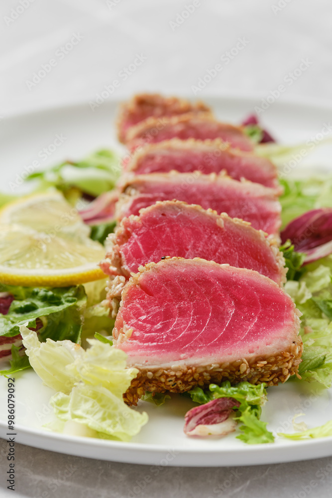 Freshly seared tuna slices served on a bed of greens with lemon wedges for a vibrant meal Freshly seared tuna slices served on a bed of greens with lemon wedges for a vibrant meal
