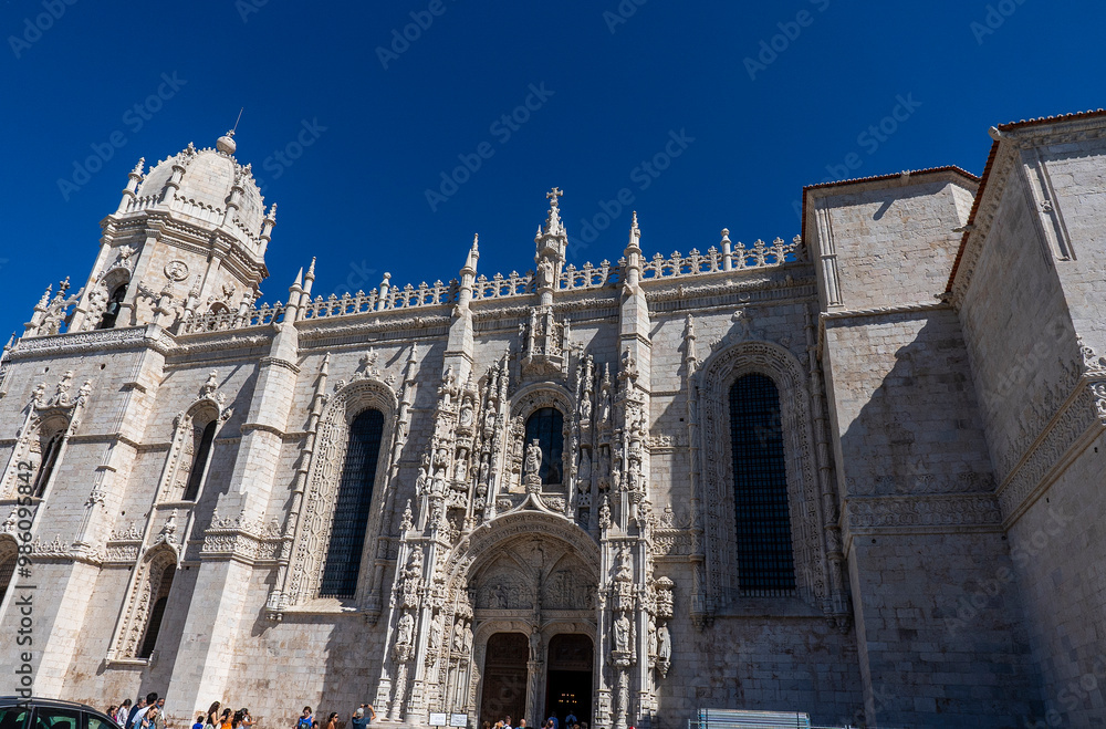 Fototapeta premium Tourists visit The Jerónimos Monastery , one of the most prominent examples of the late Portuguese Gothic Manueline style of architecture in Lisbon,erected in 1500s. Portugal, Europe.