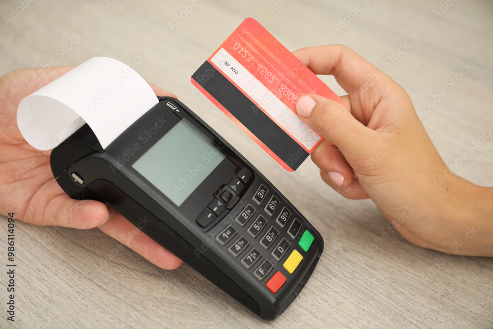 Man taking payment from client via credit card terminal at wooden table, closeup Man taking payment from client via credit card terminal at wooden table, closeup