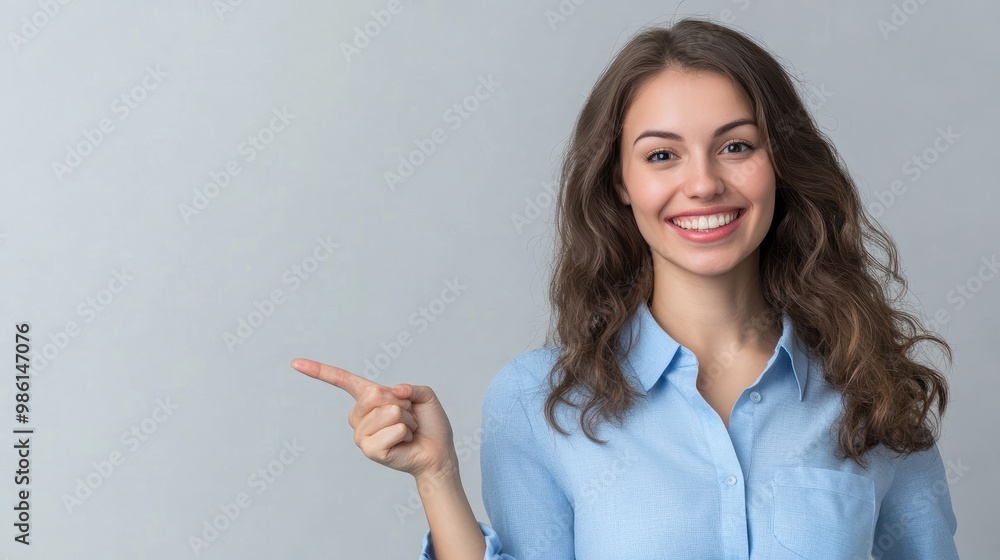 Happy young smiling professional business woman wearing blue shirt looking at camera pointing finger away at copy space showing aside presenting advertising offer standing isolated at gray background. Happy young smiling professional business woman wearing blue shirt looking at camera pointing finger away at copy space showing aside presenting advertising offer standing isolated at gray background.
