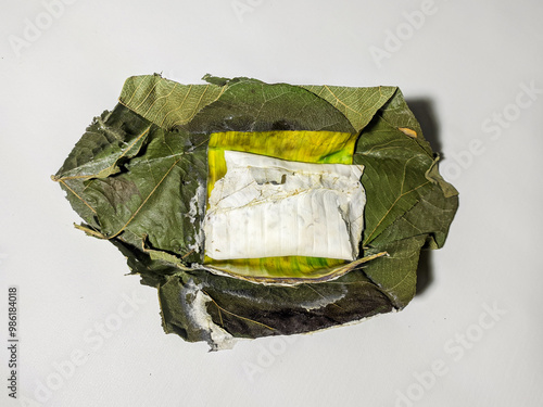 Traditional tempeh wrapped in teak leaves isolated on a white background. Tempeh is a popular Indonesian food made from fermented soybeans. It is tastier and healthier than being wrapped in plastic. photo