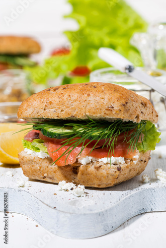 sandwich with salted fish, fresh vegetebles and cream cheese on wooden board, vertical closeup photo