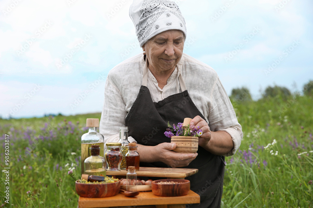 Senior woman with mortar and pestle making tincture outdoors Senior woman with mortar and pestle making tincture outdoors