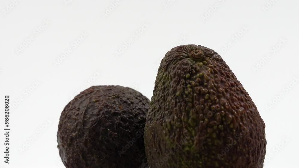 Two avocados sitting on top of each other. Avocados are brown in color and have a fuzzy texture. Avocado rotates on a white background. Two avocados sitting on top of each other. Avocados are brown in color and have a fuzzy texture. Avocado rotates on a white background.