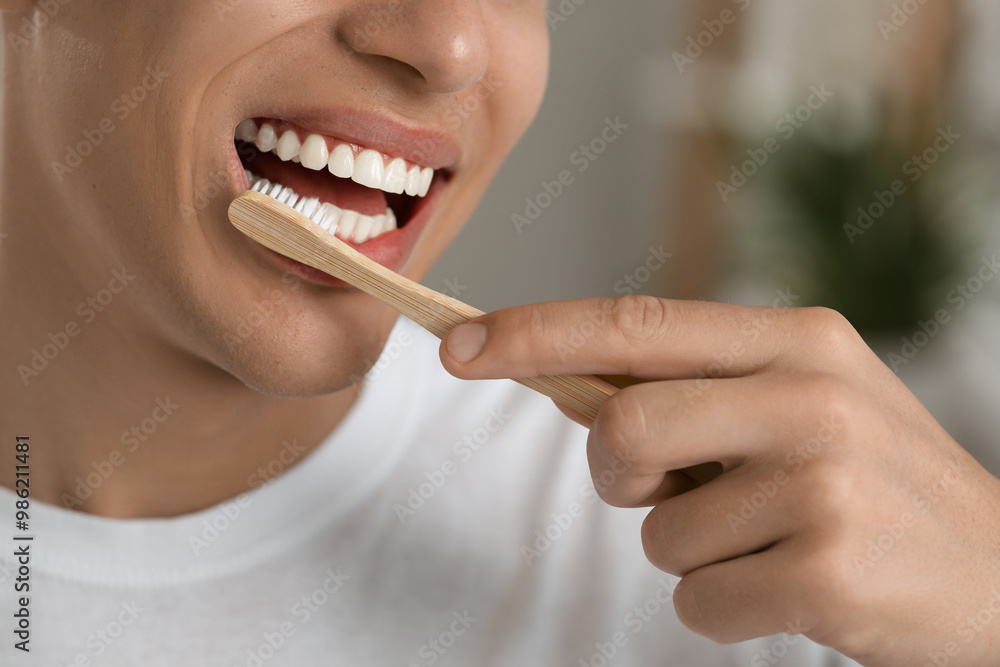 Young man brushing his teeth in bathroom, closeup Young man brushing his teeth in bathroom, closeup