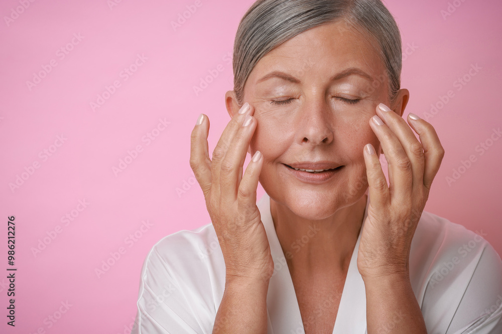 Beautiful woman doing facial massage on pink background Beautiful woman doing facial massage on pink background