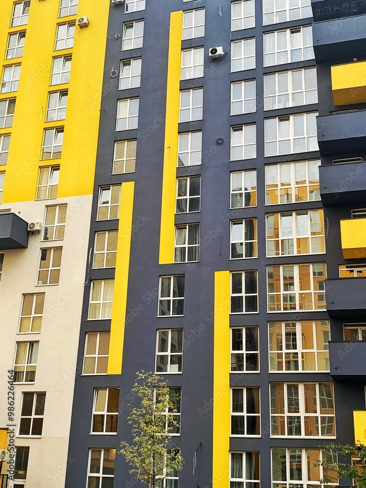 Fototapeta premium Architecture Background. Detail New high-rise Building or House Modern facade with windows. Contemporary geometrical architectural design backdrop. Real Estate concept. Yellow and Gray-Dark blue color