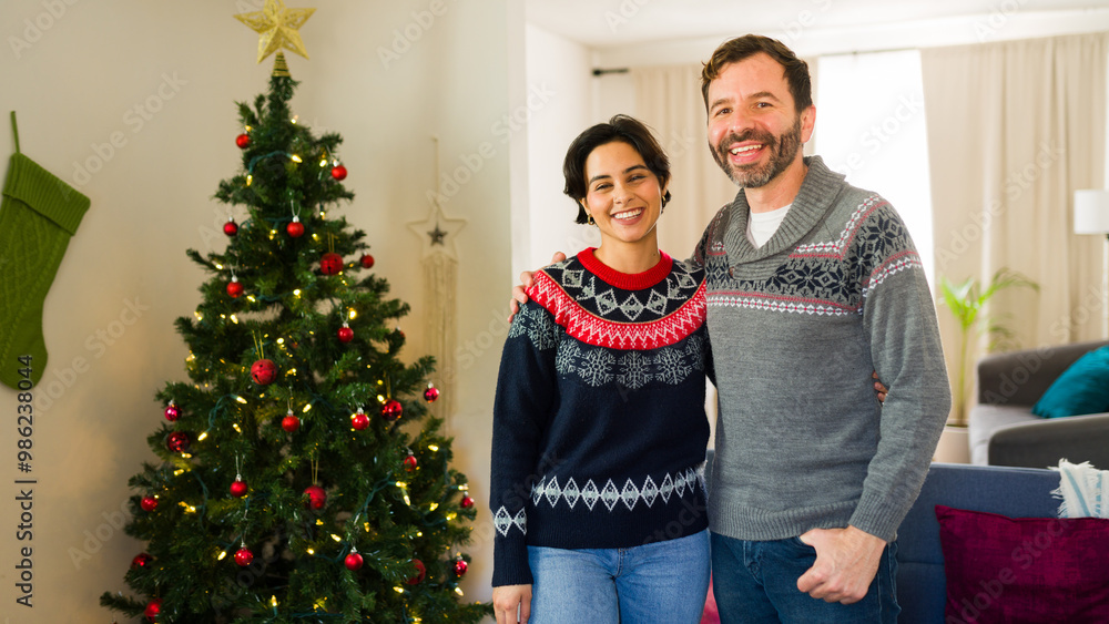 Happy couple in festive sweaters sharing a warm embrace and celebrating the holidays at home Happy couple in festive sweaters sharing a warm embrace and celebrating the holidays at home