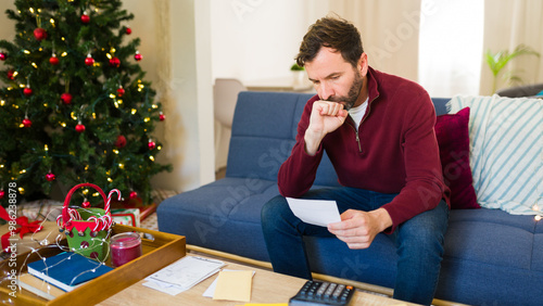 Canvas-taulu Man anxiously tallying up his holiday spending and clutching a receipt