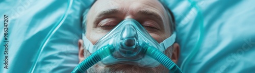 A close-up of a patient wearing an oxygen mask, lying on a bed with soft blue linens, suggesting a medical or hospital setting. photo