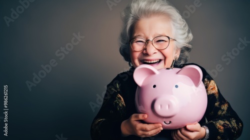 An elderly woman joyfully holding a pink piggy bank, conveying happiness and financial security in her golden years. photo