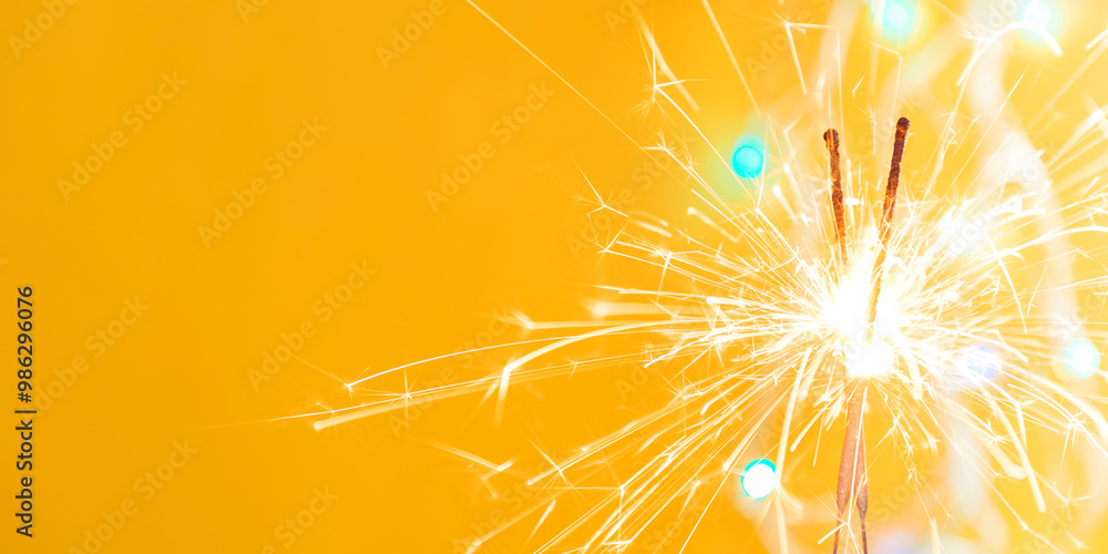 Obraz premium Beautiful glowing sparklers on colored background. Colorful sparklers sparkling against vibrant yellow bokeh background creating festive and celebratory atmosphere. Christmas mood festive yellow back