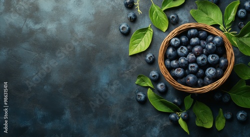 Fresh blueberries in a woven basket with green leaves on a dark textured surface