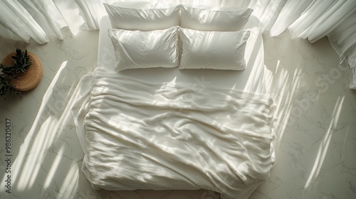 Cozy white bed with rumpled blankets and pillows in a minimalist bedroom setting