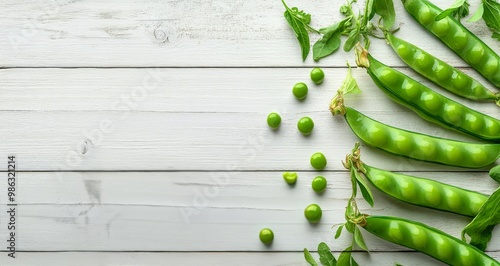 Fresh green peas and pods arranged on a rustic wooden table with scattered peas